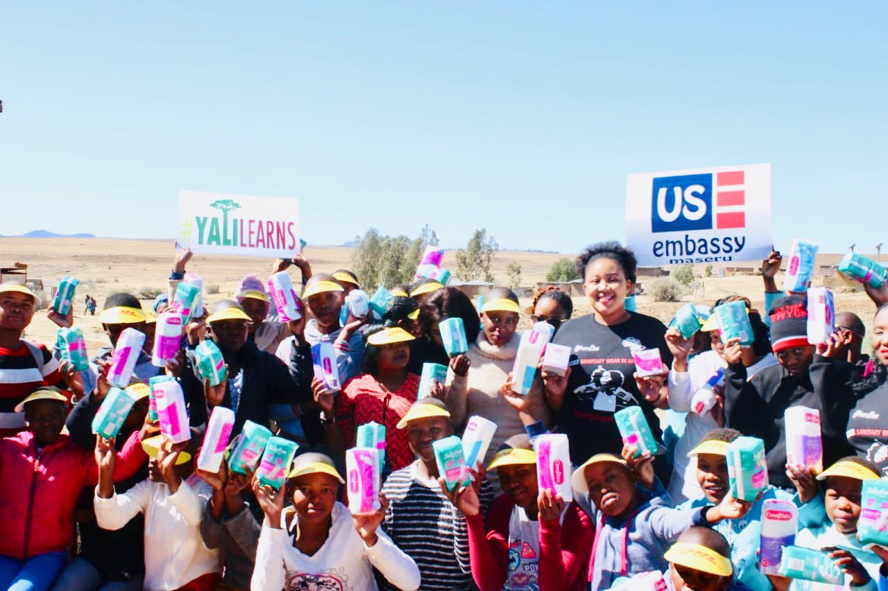 Community members holding menstrual hygiene products during an outreach program